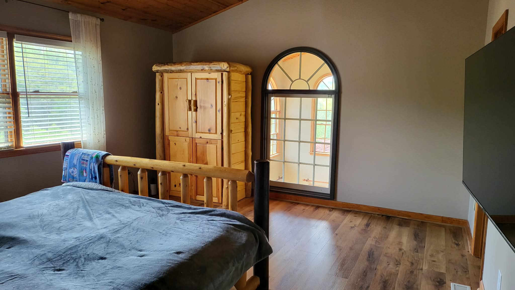 Master bedroom with log furniture, arched window overlooking the great room
