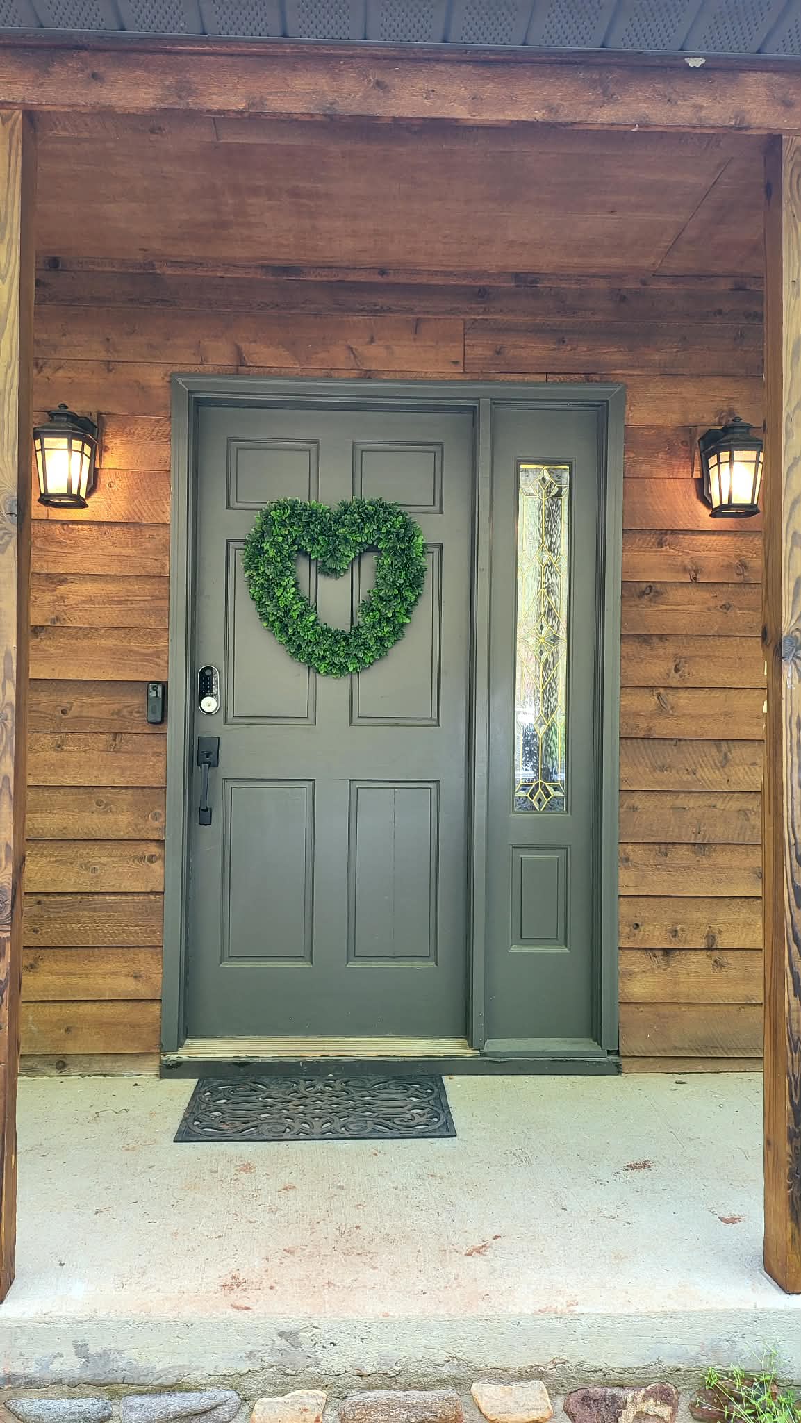 Welcoming front entrance with wreath, cedar siding, and craftsman lanterns