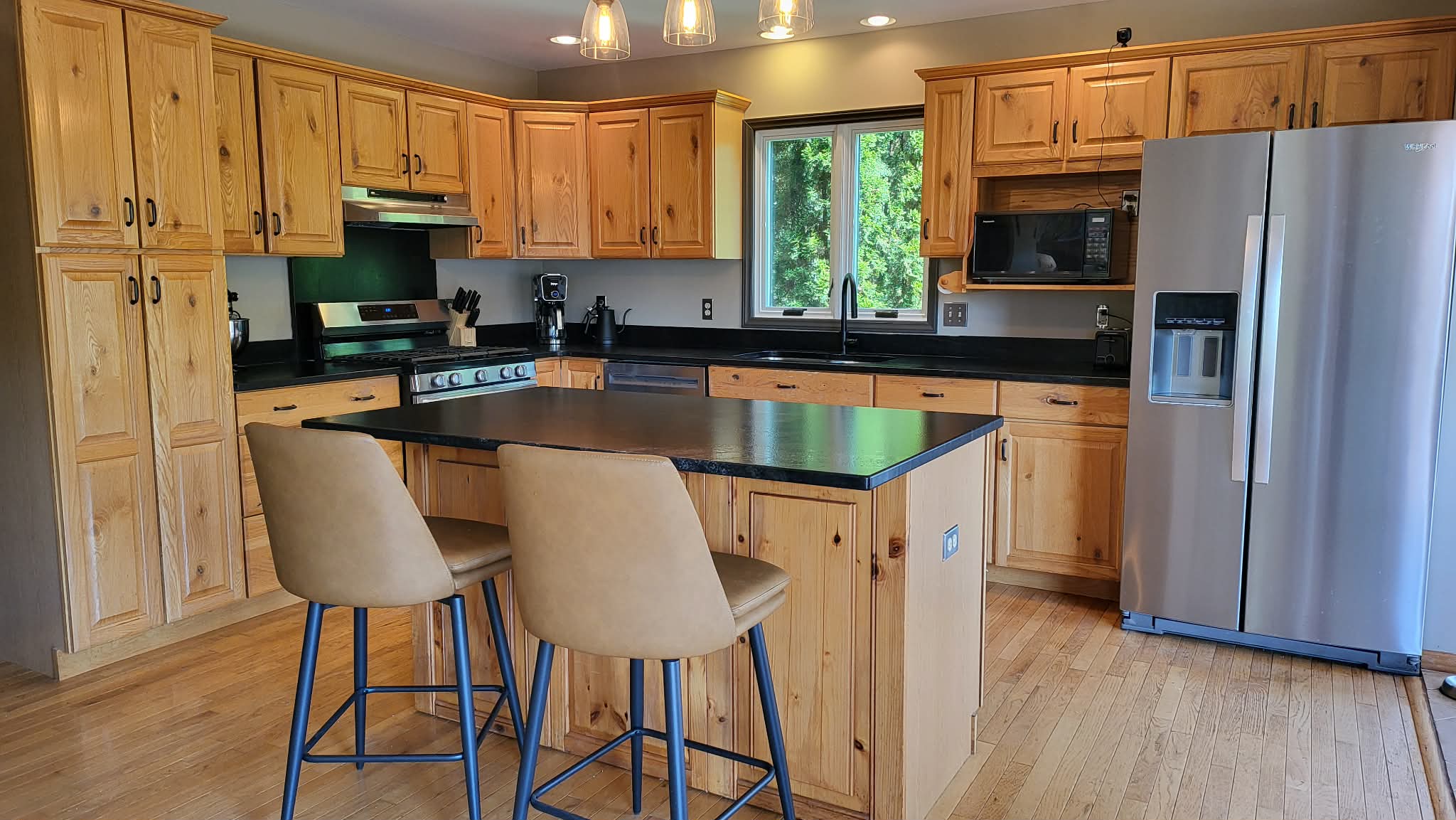 Chef's kitchen with knotty wood cabinets, black countertops, and island seating