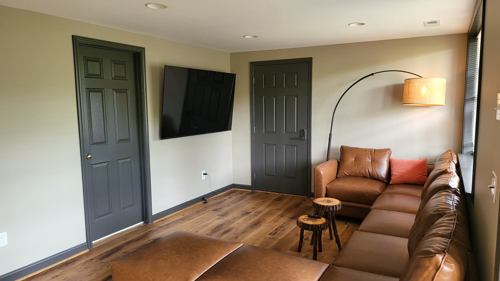 Lower level lounge with leather sectional and rustic wood floors
